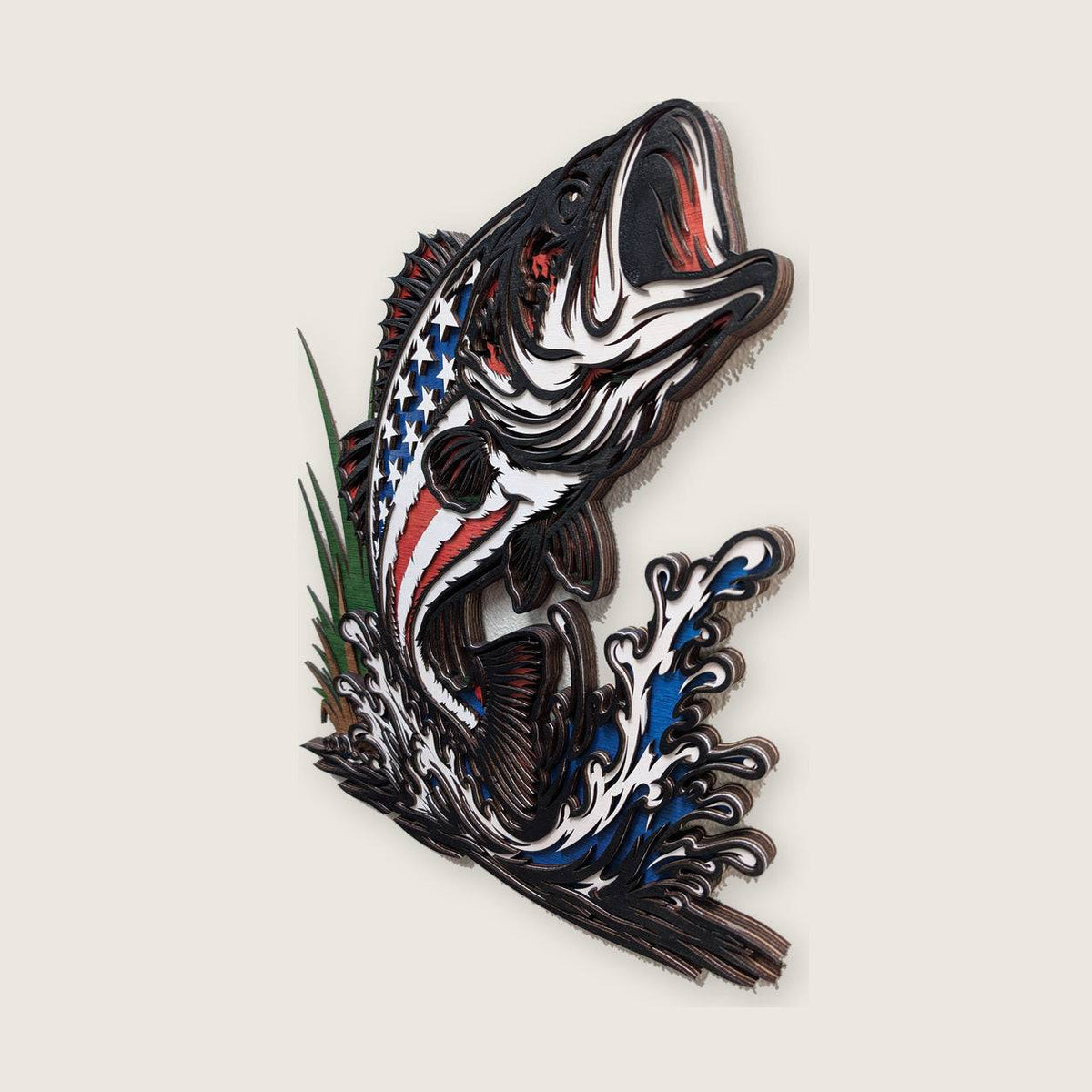 A 3D layered wooden wall art piece depicting a leaping fish with an American flag pattern on its body, set against a light beige background.