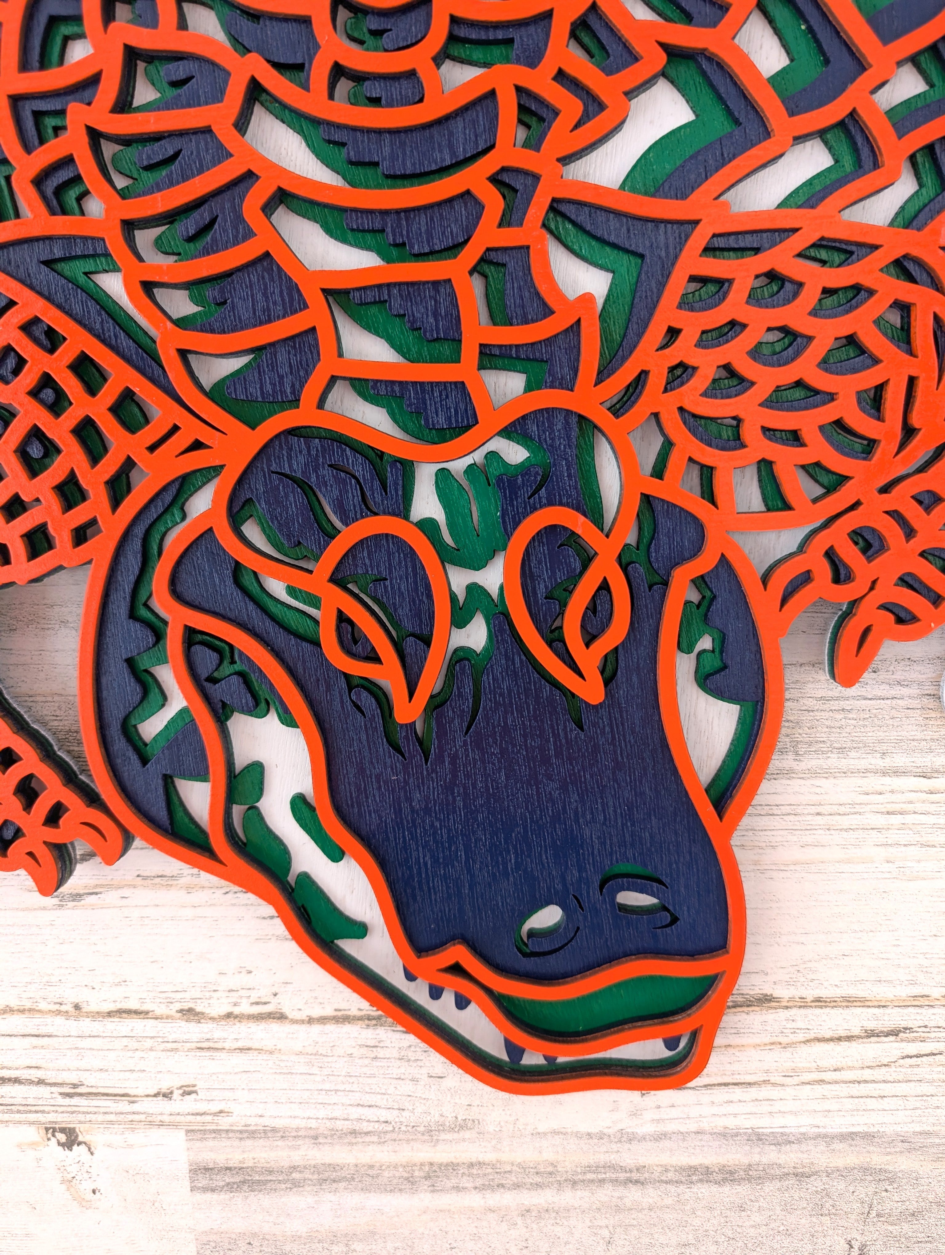 Wooden cutout of a dragon design with orange, blue, and green colors on a wooden surface.