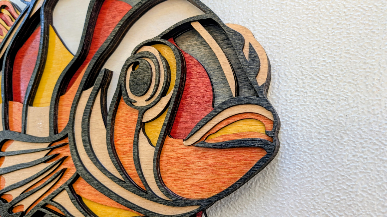 Wooden fish sculpture with colorful inlay on a white background