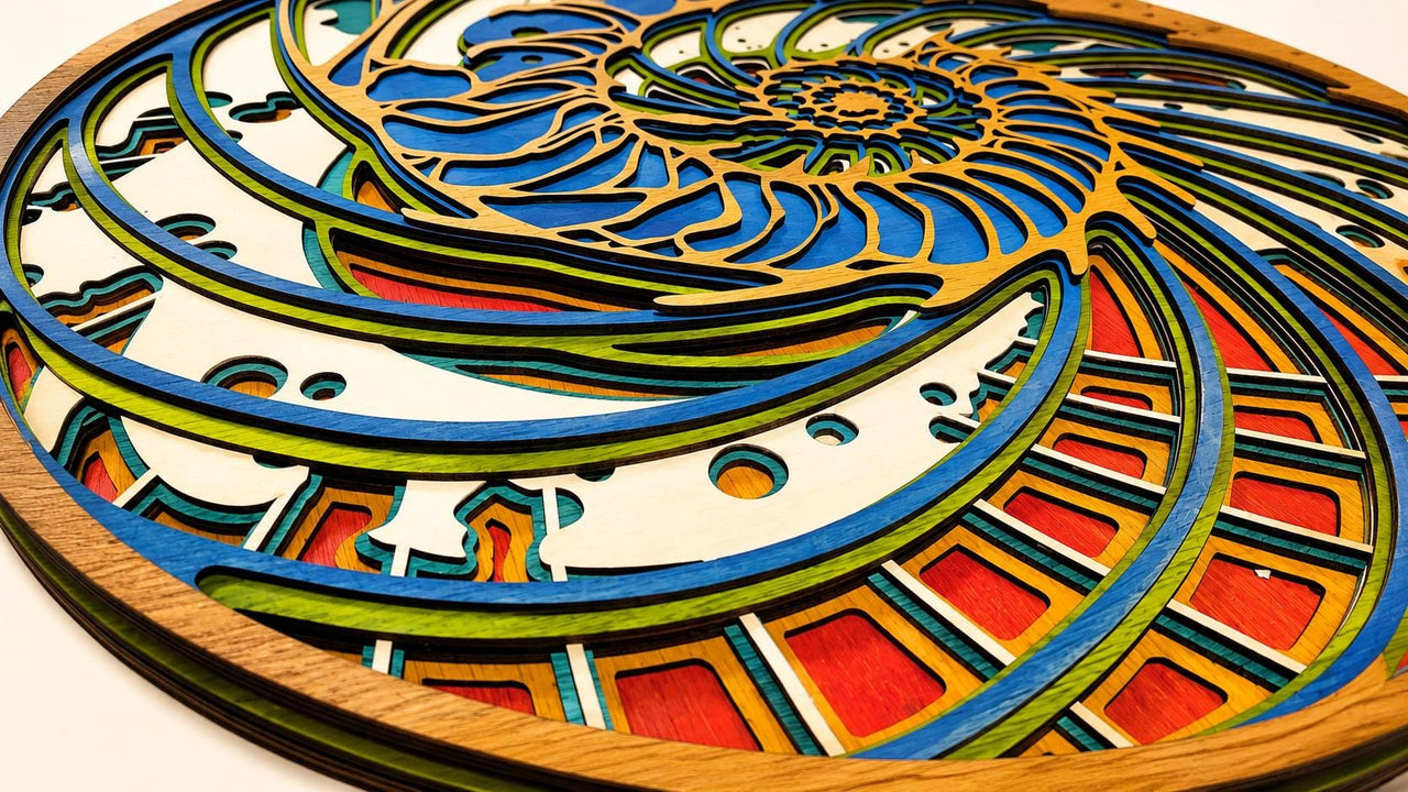 A layered wooden art piece with a spiral design. The artwork features multiple layers of wood in various colors, including blue, green, red, and natural wood tones. The design is reminiscent of a nautilus shell.