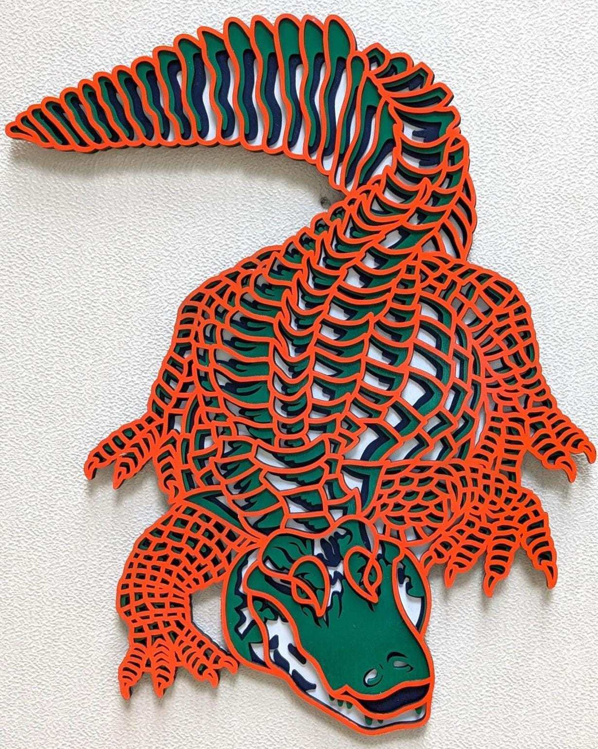 Layered Alligator Wall Art in colorful green, navy, gray and orange laser-cut wood with detailed scales and curled tail