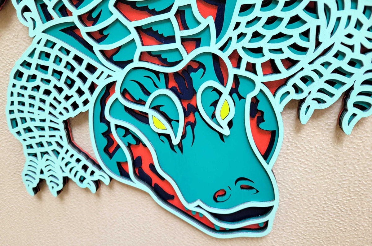 Layered Alligator Wall Art featuring a turquoise wooden alligator face with navy, red, and yellow layered details