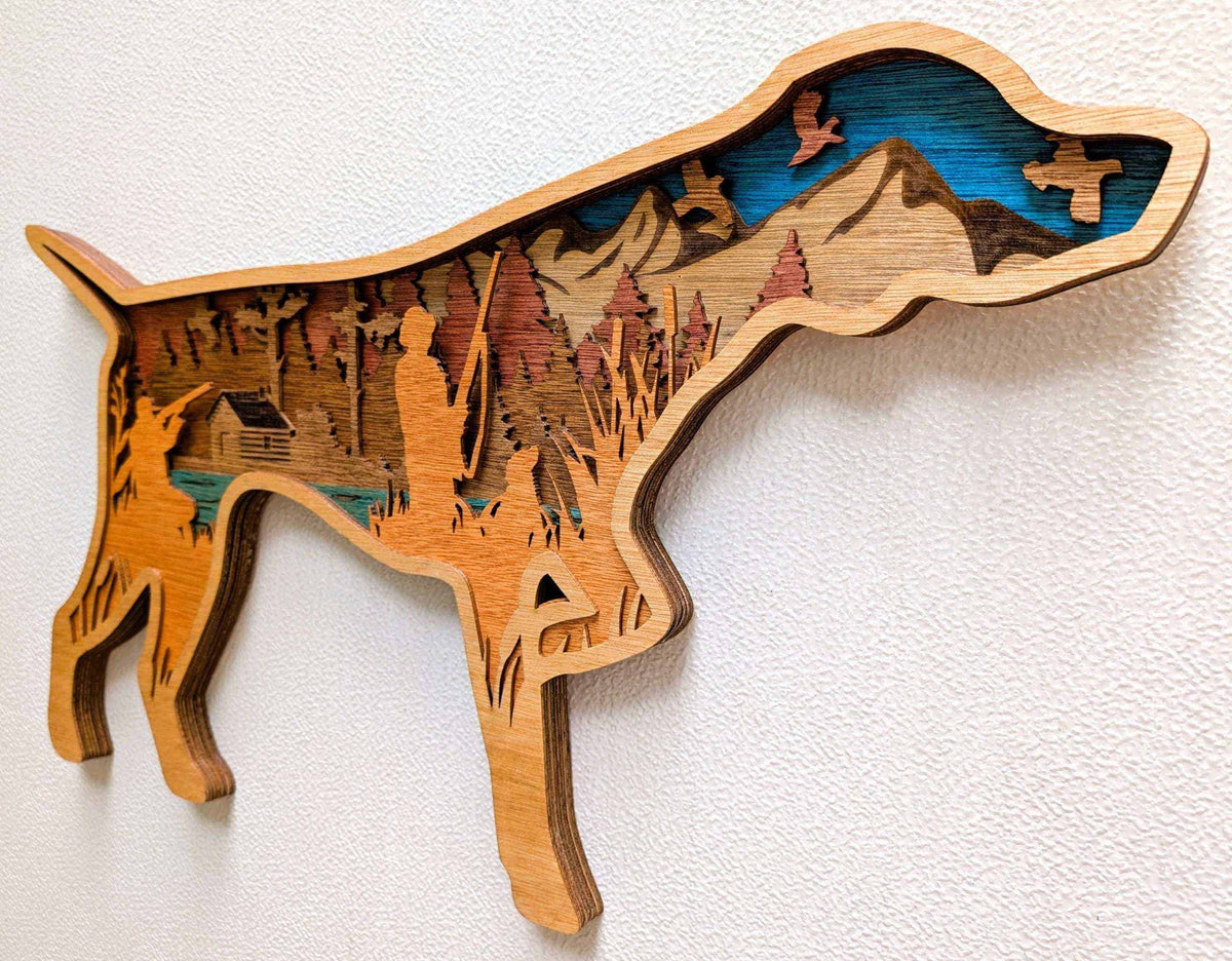 Layered Hunting Dog Wood Wall Art featuring a tan wooden hunting dog silhouette with mountain, forest, cabin, water, and bird details