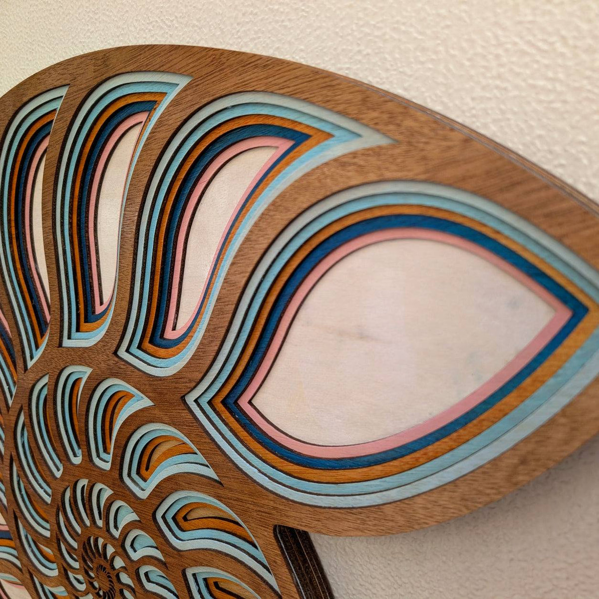 Handmade layered wood nautilus shell wall art with coastal ocean decor colors and intricate spiral design